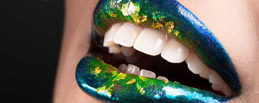 Green and blue sparkled lips contrasting against the gleaming white teeth